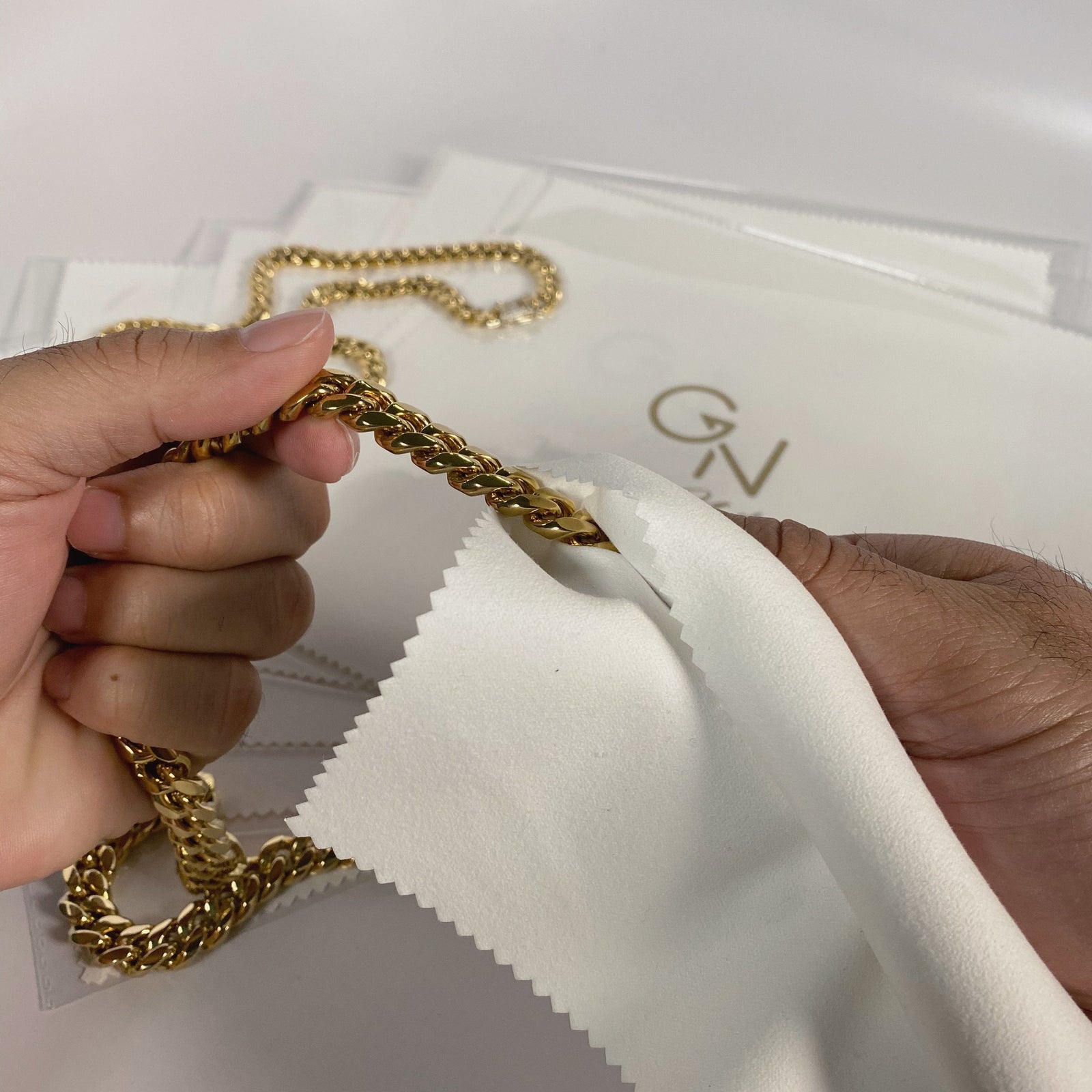 gold plated Cuban chain men's jewelry being cleaned with a microfiber cloth